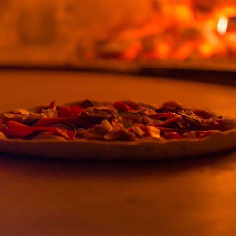 Pizza next to pizza oven